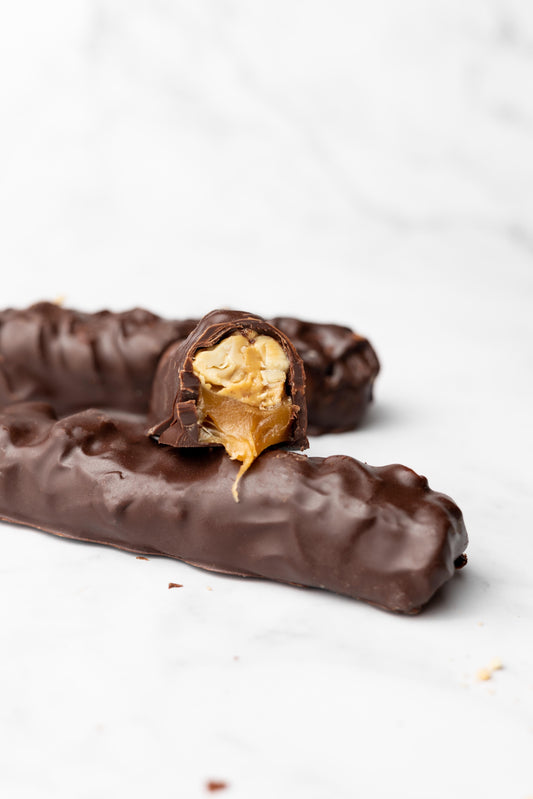Side profile of unwrapped candy bar atop a lengthwise candy bar